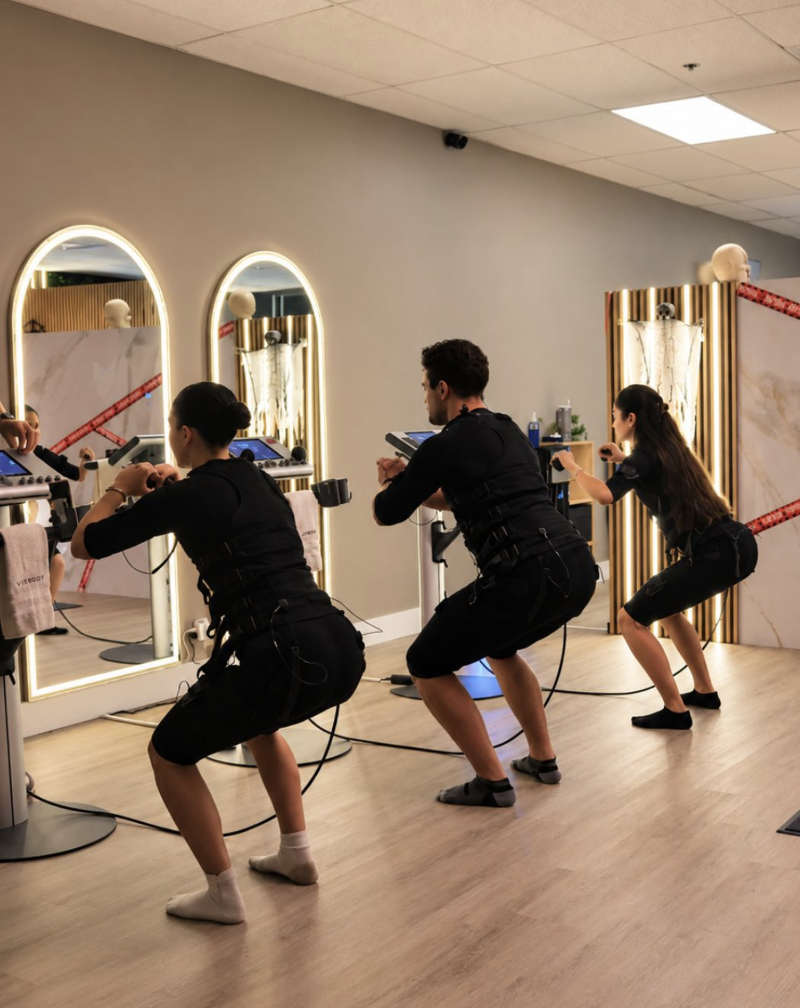 Group EMS class squatting in front of lit mirrors